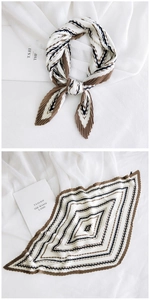 Detail of pleated silk scarf featuring beige, brown, and black geometric striped patterns