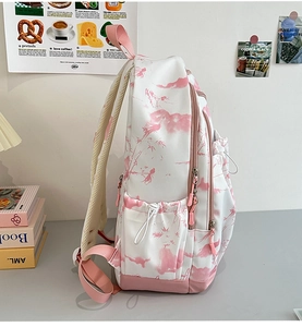 Détail de poche latérale avec cordon et imprimé paysage rose sur le sac à dos