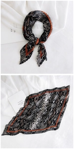 Macro detail of pleated scarf featuring snakeskin print and contrasting orange borders