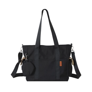 Large black canvas tote bag with adjustable shoulder strap and a small coin purse charm