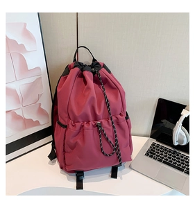 Detail view of deep red waterproof nylon drawstring backpack with front elastic pocket