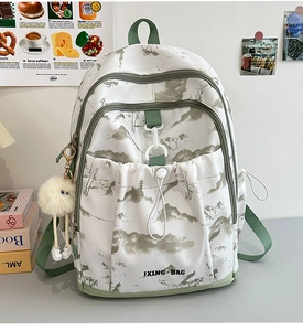 Détail du sac à dos blanc avec imprimé paysage à l'encre verte et pendentif en peluche