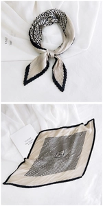 Detail of pleated square scarf featuring beige and black geometric diamond pattern