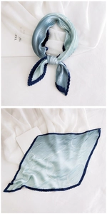 Detail of light blue pleated silk scarf with dark blue edges and white wavy line patterns