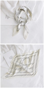 Detail of white pleated neck scarf featuring black geometric LOVE pattern and edge stitching