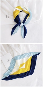 Detail of color-block pleated square scarf with navy blue and yellow diagonal patterns