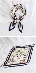 Detail of a white pleated silk scarf with vintage gold chain prints and navy borders