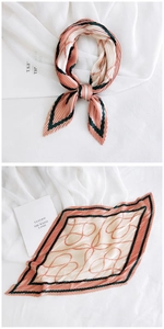 Detail of pleated silk scarf featuring pink heart patterns and contrast green borders