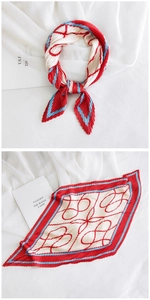 Detail of pleated silk scarf showing red and blue geometric patterns on white linen
