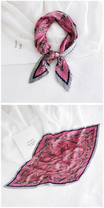 Detailed close-up of pink pleated silk scarf with vintage chain print and blue borders