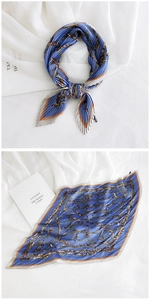 Detail of blue pleated square scarf featuring vintage chain prints and orange border edges