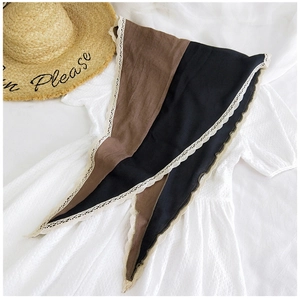 Detail of color-block scarf with white lace trim on a white embroidered dress background