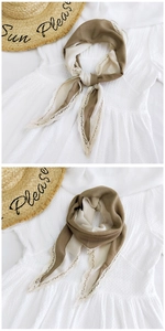 Close-up of khaki and cream silk scarf with elegant lace trim on white dress