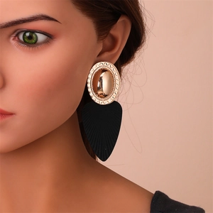 Détail de boucles d'oreilles feuilles bicolores avec métal doré texturé et goutte noire
