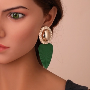 Gros plan de grandes boucles d'oreilles rétro avec métal doré et feuilles vertes texturées