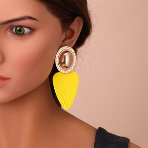 Détail macro de grandes boucles d'oreilles feuilles jaunes avec clous ovales dorés ondulés