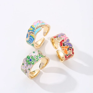 Macro shot of 18K gold plated adjustable rings with colorful enamel floral patterns