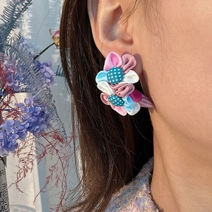 Boucles d'oreilles fleurs en tissu faites main en rose et bleu portées par un mannequin