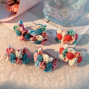Vue détaillée de cinq barrettes à fleurs en tissu fait main sur un fond en peluche douce