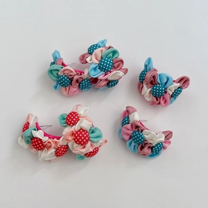 Détail de boucles d'oreilles fleurs en tissu faites main avec boutons à pois centraux