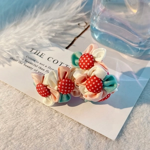 Détail de boucles d'oreilles fleurs en tissu fait main avec boutons à pois sur fourrure