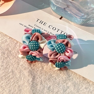 Détail macro de boucles d'oreilles fleurs en tissu faites main sur fond blanc doux