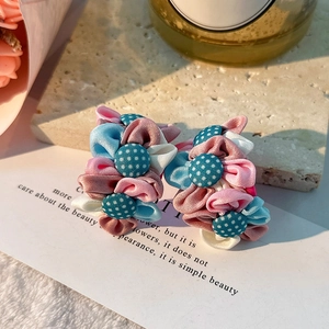 Détail de boucles d'oreilles fleurs en tissu fait main avec pétales en mousseline douce