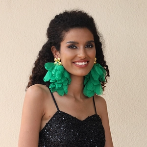 Macro detail of oversized green fabric flower tassel earrings with gold accents on model