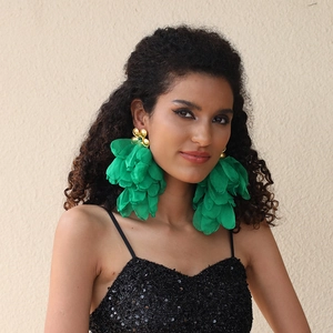 Macro detail of oversized green layered fabric flower earrings with gold petal studs on a model