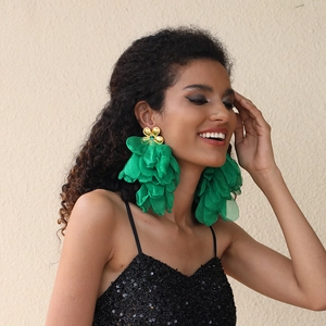 Detail of oversized handmade green fabric flower earrings with golden floral studs
