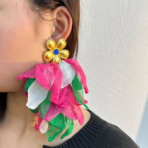 Macro view of handmade floral tassel earring with gold petals and a blue gemstone