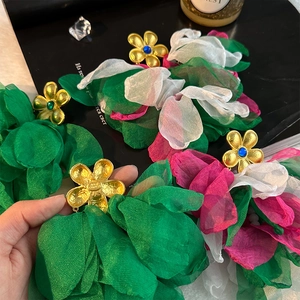 Detailed macro view of large handmade fabric flower earrings with vibrant layered petals