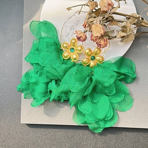 Detail of emerald green fabric flower earrings with gold stamens and gemstone