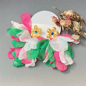 Macro detail of handmade floral tassel earrings with fabric petals and gold metal studs