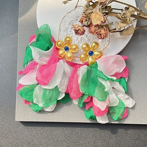 Close-up of handmade floral tassel earrings with silk petals and gold metal flower top