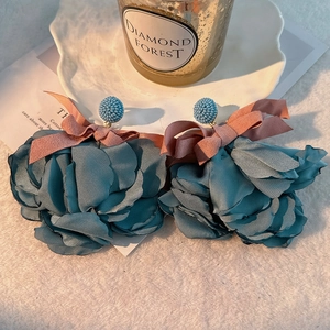 Detail view of large multi-layered fabric flower earrings with pink silk bows