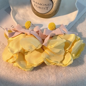 Detail of yellow fabric floral earrings with pink ribbons and bead center on soft white fur