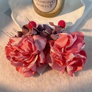 Detail of pink silk fabric flower earrings with purple bows and beaded studs