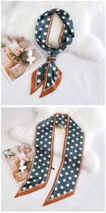 Gros plan sur un foulard en soie à pois bleus avec bordure orange et texture satinée