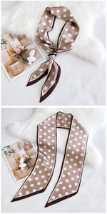 Vue détaillée d'un foulard en soie à pois noué sur un magazine avec fond en peluche blanc
