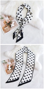 Détail d'un long foulard en soie à pois noirs sur fond blanc avec texture douce