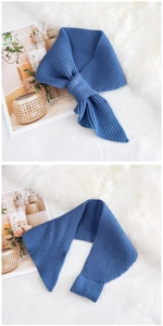 Detailed view of dark blue ribbed knit scarf texture on a soft white plush background