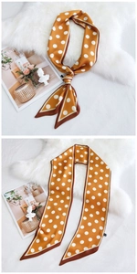 Détail d'un foulard en soie jaune à pois attaché sur un magazine avec fond en peluche