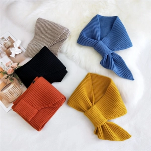 Chic knit cross scarf in five colors displayed on soft white fur backdrop for winter