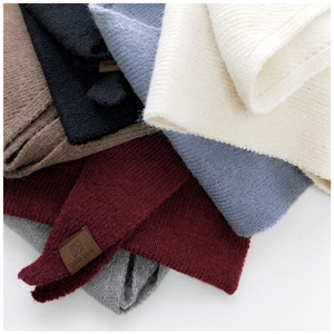 Detail of knitted triangle scarves in multiple colors with leather logo labels