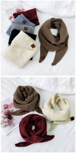 Detail view of multicolored knitted scarves showing premium texture and leather brand label