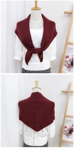 Detail of burgundy knitted shawl with vertical ribbed texture and leather logo tag
