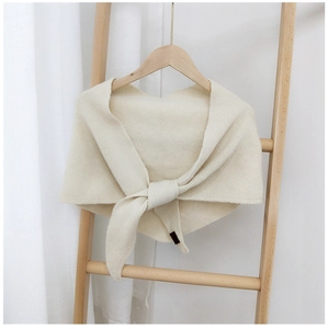 Close-up of cream knitted triangle shawl featuring delicate vertical stripe textures