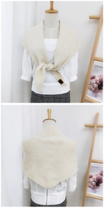 Detailed knit texture of a beige triangular scarf with elegant leather label accent