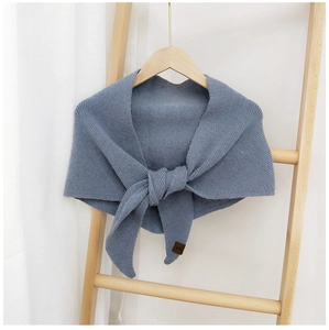Detail of blue knitted shawl featuring fine stitching and a small brown leather tag